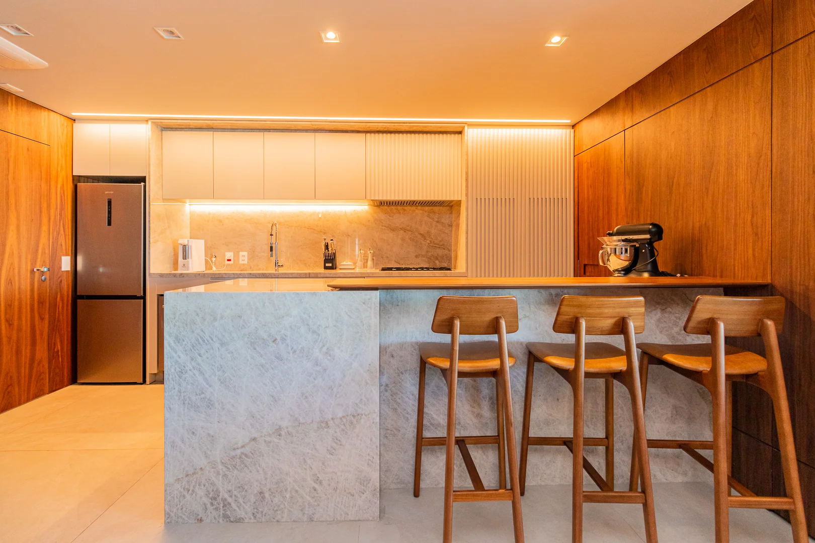 Cozinha com bancada de pedra e iluminação quente